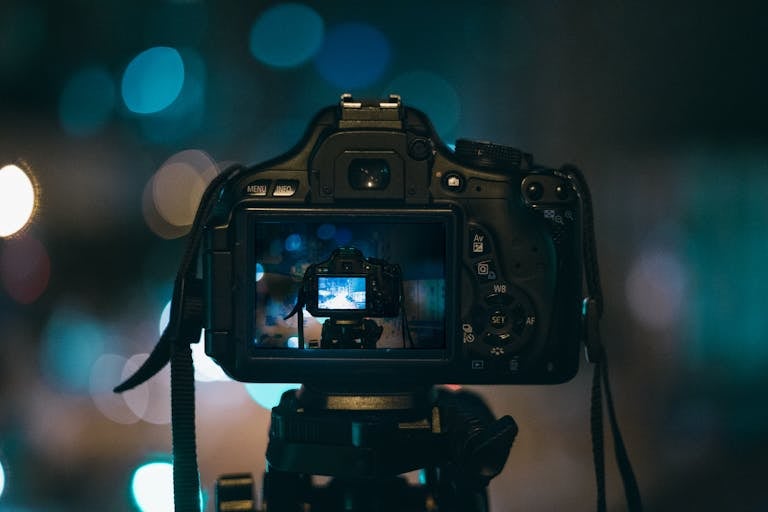 Close-up of a DSLR camera capturing a bokeh background in a dimly lit setting, illustrating night photography.